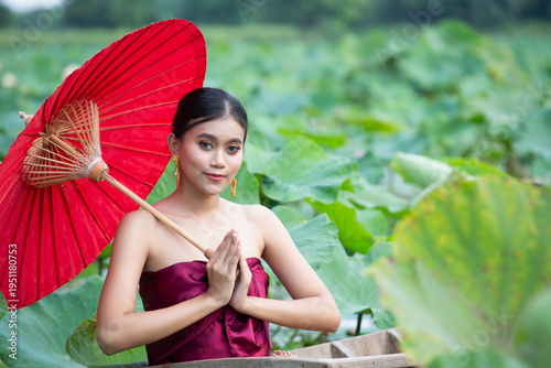 Canvas Print Young Southeast Asian woman in traditional clothing posing with red umbrella in