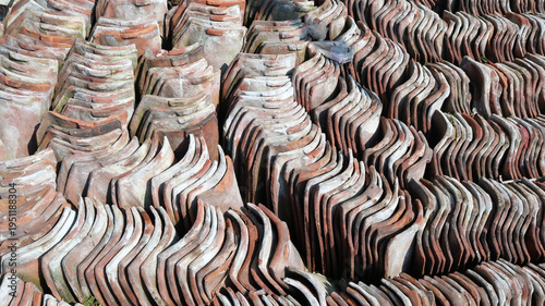 Photography Rows of weathered terracotta roof tiles neatly stacked outdoors, creating an int