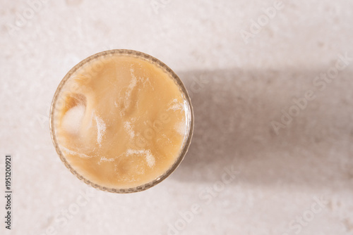 Macro Top View of Iced Caramel Cappuccino  in Clear Glass on Beige Background, Minimalist Coffee Aesthetic, Copy Space, Refreshing Cold Drink Concept
