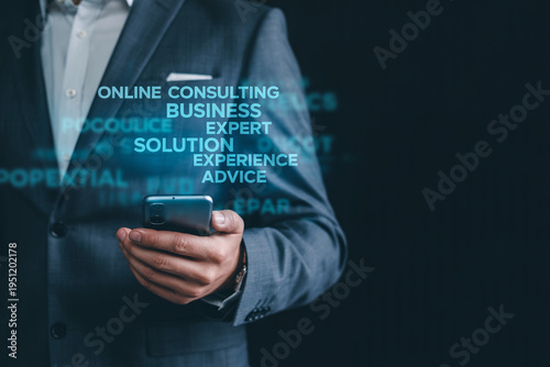 Businessman in formal suit holding smartphone with holographic text regarding online consulting and business expert advice