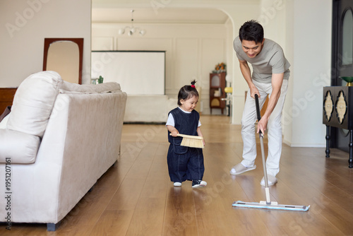 A stay-at-home dad cleaning the house with his baby girl as his little helper