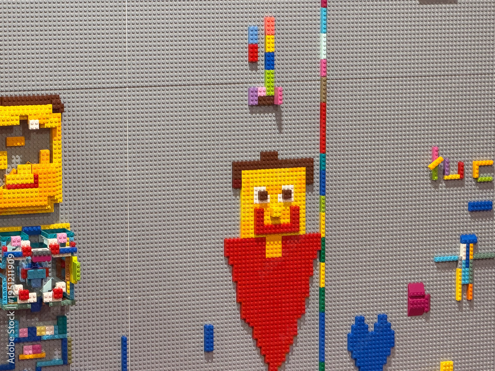 Fototapeta premium Colorful toy brick pixel art character on studded wall