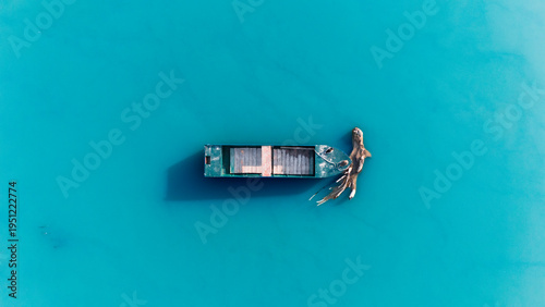 Aerial view of a weathered boat adrift in the turquoise expanse, its decaying wood stark against the azure water, Novi Sad, Vojvodina, Serbia.