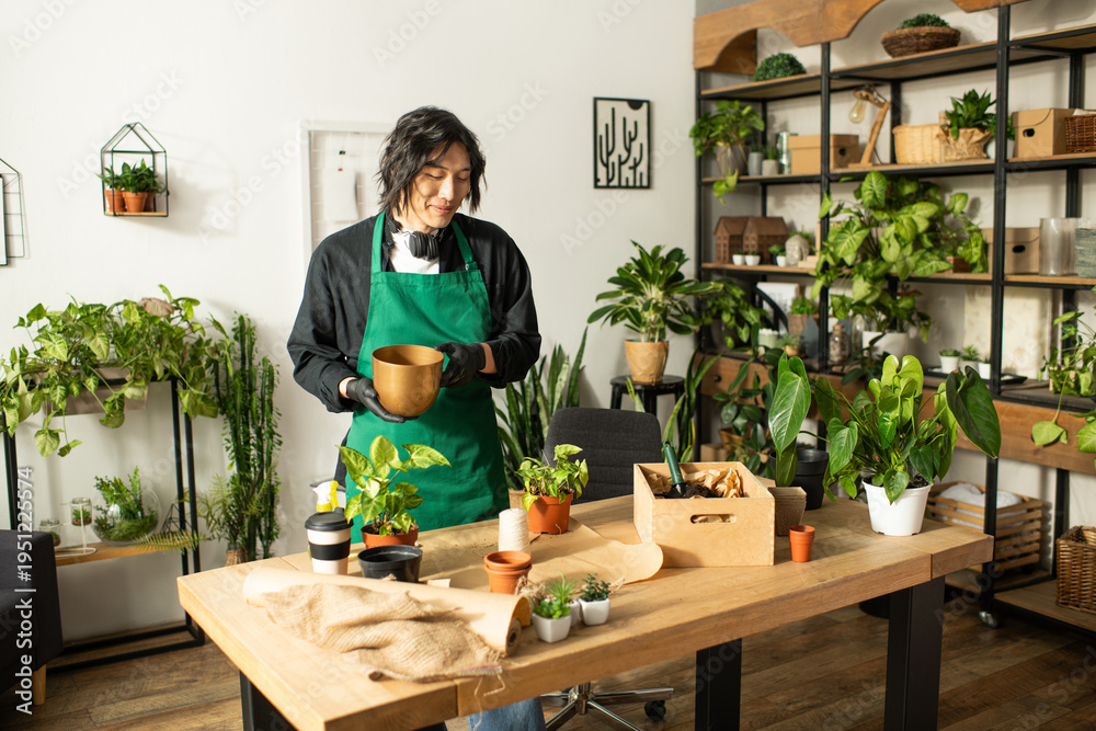 Fototapeta premium Young Asian florist engaging with plants in a cozy flower shop filled with greenery