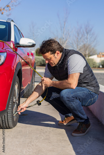Man checking car tire pressure at petrol station
