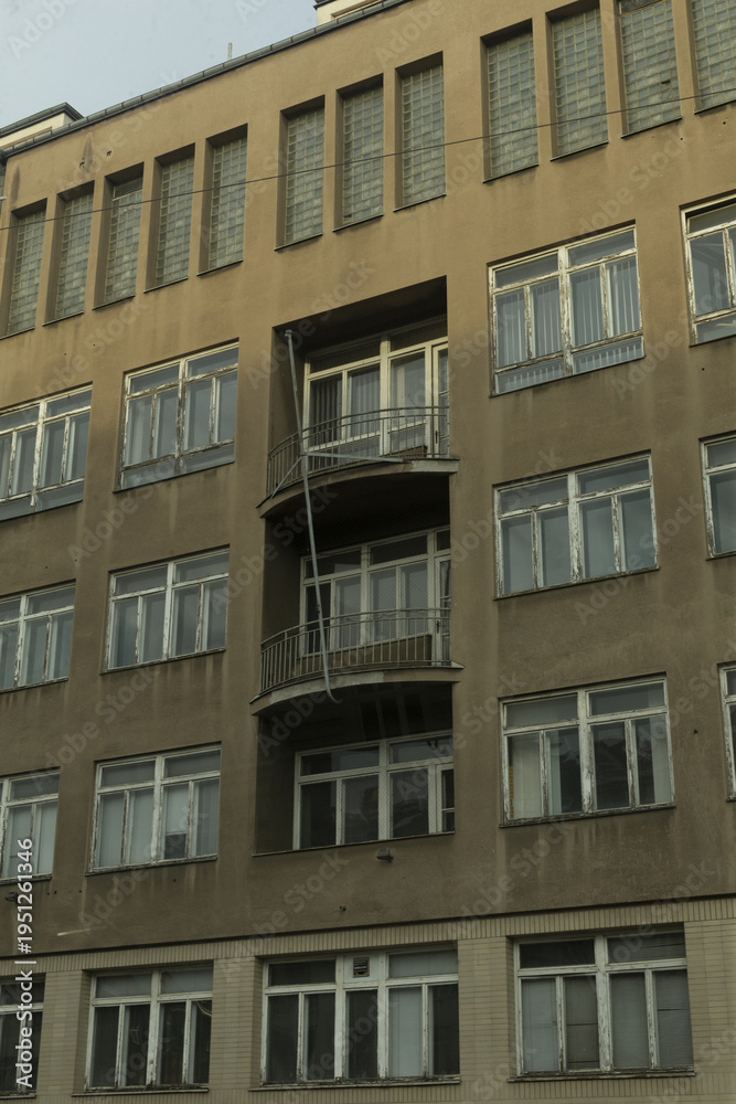 Obraz premium Concrete apartment block with stacked balconies, repetitive windows, weathered concrete, small metal railings, utilitarian