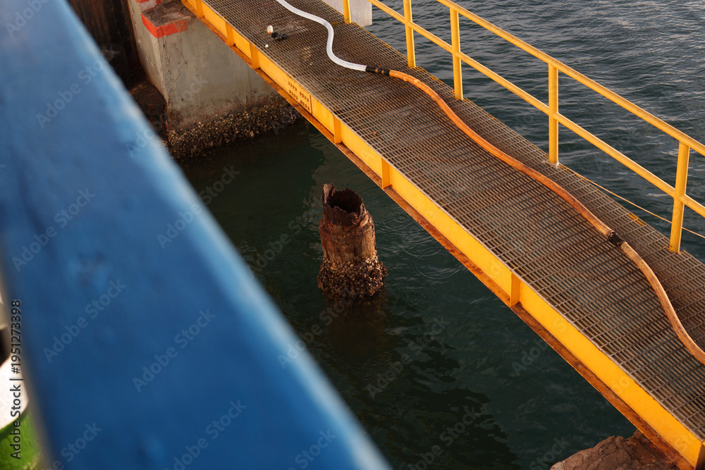 Fototapeta premium Pier bridge at Kayangan Port, Lombok with ferry moored and dock workers handling ropes