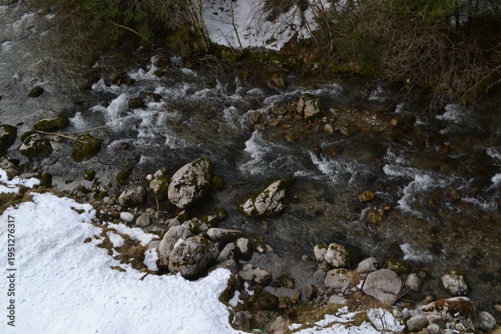 Fototapeta premium Aerial View of Mountain River Flowing Through Snowy Landscape