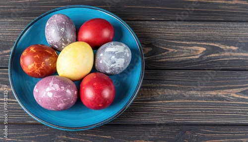 painted colored Easter eggs on a blue plate on a dark wooden background