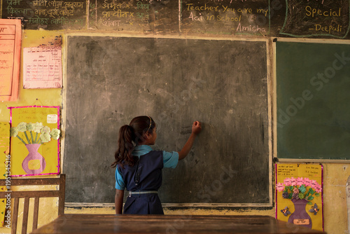 Rural indian school girl writing on black board