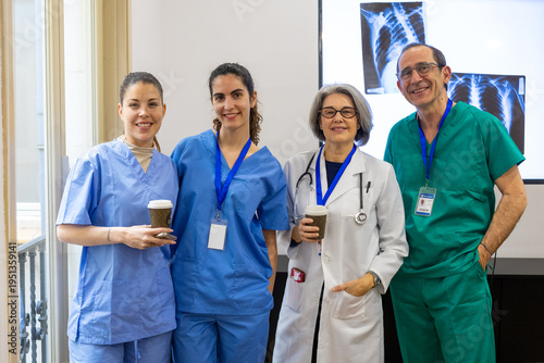 Diverse medical team smiling, holding coffee cups