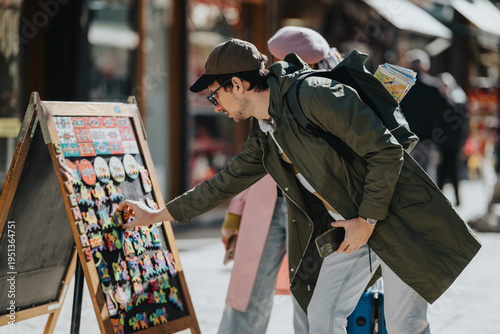 Canvas Print Diverse tourists browse a display of colorful souvenir magnets at an outdoor market