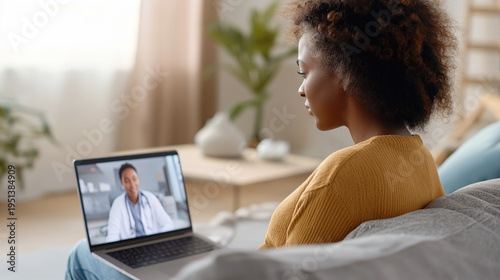 Young African American woman having a remote video call with doctor on her laptop at home. Modern telemedicine, online medical consultation and virtual healthcare service concept