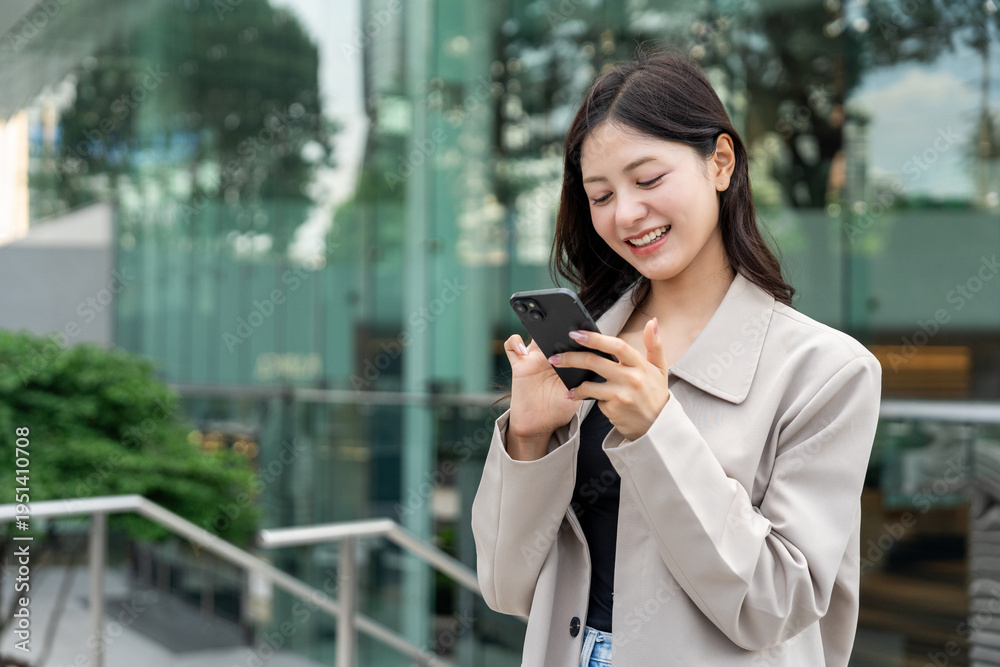 Fototapeta premium Beautiful business woman using mobile phone while walking business buildings. Smart female using cell phone chatting for business communication talking. Business lifestyle concept.