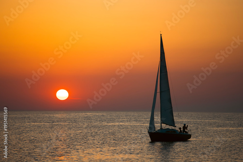 Sailing boat silhoutted against the orange sky