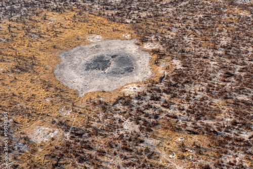An aerial of a dry pool in the middle of woodland and grassland during the hot season in Okavango delta, Botswana