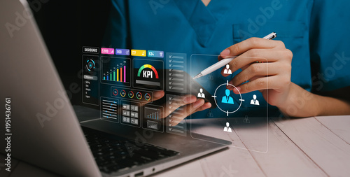 Business analytics concept. Healthcare worker using laptop and stylus interacting with virtual KPI dashboard and employee targeting interface, data analytics management, performance monitoring