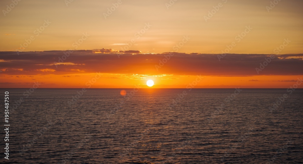 Obraz premium Glorious sundown casting radiant gold over vast sea framed by impressive cloud layers