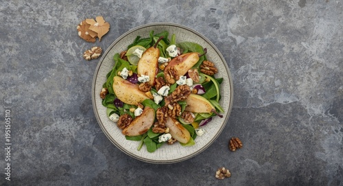 Overhead image of gray stone grain background displaying French autumn salad with pears walnuts and blue cheese alongside copy space