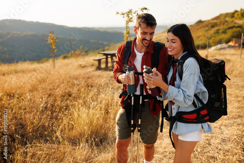 Active couple taking a hiking break relaxing and drinking water