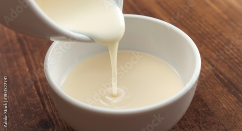 Pouring condensed milk dripping into a round bowl