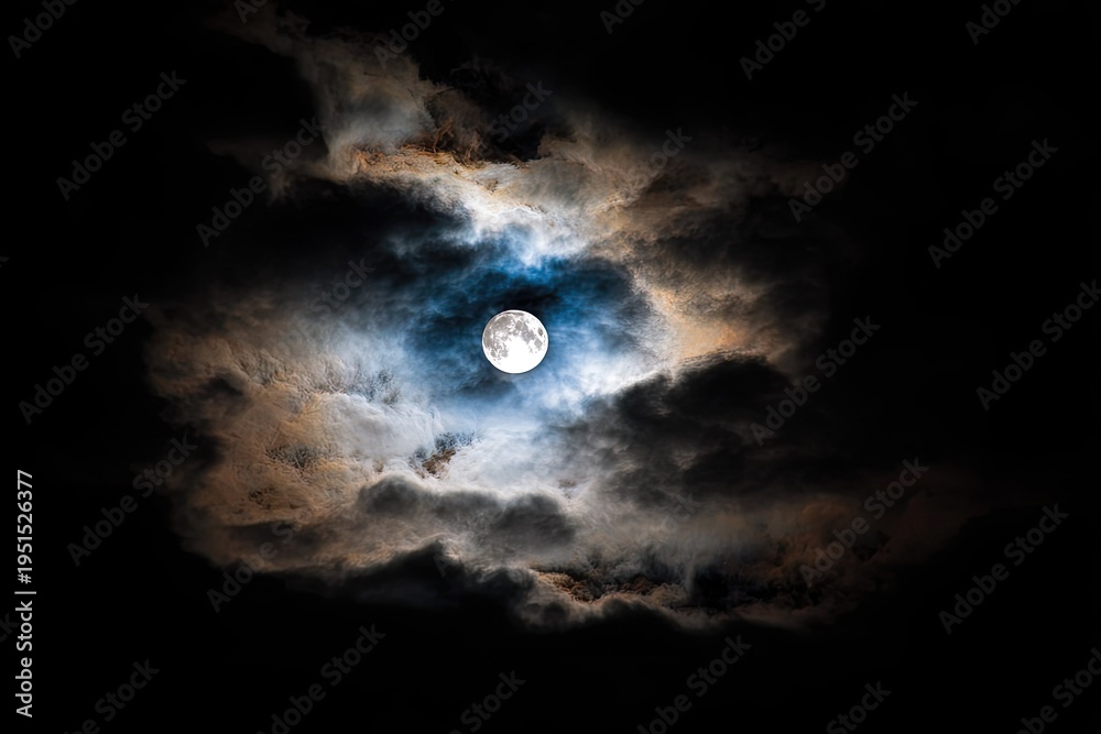 Fototapeta premium Full moon glowing brightly behind dramatic clouds at night