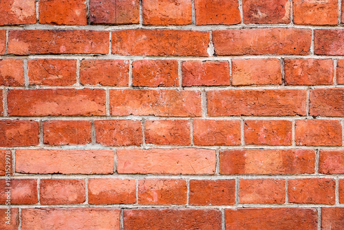 A wall made of red bricks shows a rough texture and various patterns. The bricks are placed closely with some gaps. This structure can be seen in many urban areas
