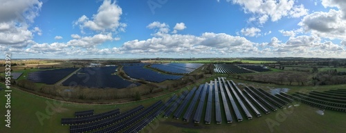 Aerial view of vast solar panel arrays gleaming under a sky brushed with clouds, juxtaposed against the green fields, Retford, United Kingdom.