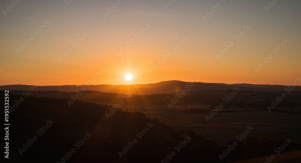 Obraz premium Sunset casting long shadows on rolling hills and rural fields
