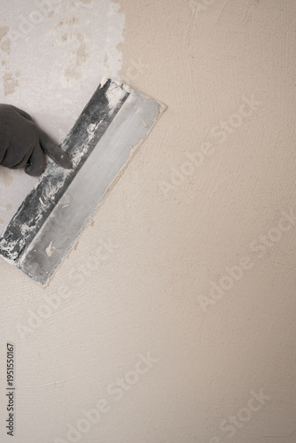 Close-up of Worker applying wall putty with spatula while smoothing wall