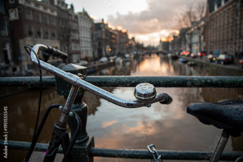 Close-up of a bicycle in Amsterdam with a canal in the background.