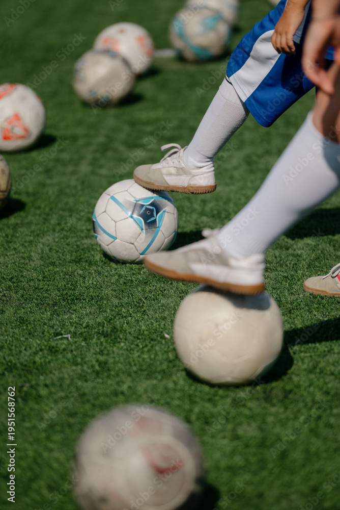 Obraz premium Children playing soccer on artificial turf with multiple soccer balls scattered