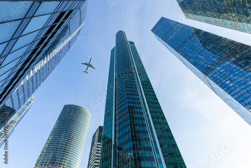 Modern glass skyscrapers and passenger plane flying over