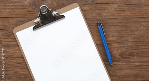 Flat lay of wooden table clipboard featuring blank paper and blue pen wide copy space for text