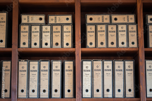 A collection of old cardboard document archive boxes neatly arranged on wooden shelves