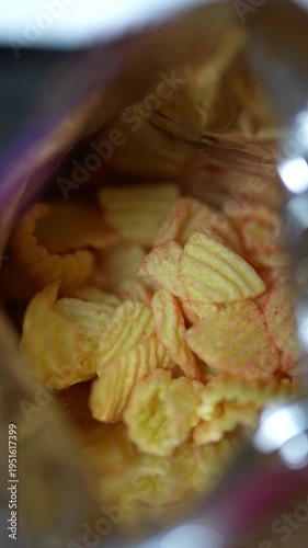 Cinematic macro shot of crispy ridged chips inside foil bag.