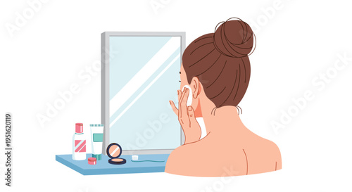 A woman with a bun applies product to her face with a cotton pad in front of a mirror.