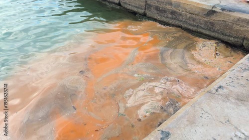 Orange water at the dock shows signs of pollution in a coastal area.