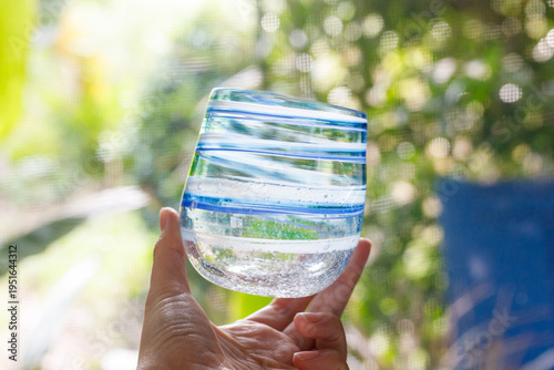 Hand holding a handmade glass cup with water
手に持ったハンドメイドガラスのグラス