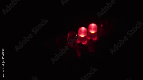 Blinking light effect on row of glowing red LEDs in dark.
