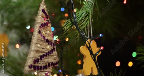 Close up of Handmade Christmas Decorations Hanging on Live Potted Aromatic Fir Tree with Sequined Ornament Knitted Snowflakes Dried Pine Cones and Live Root System for Sustainable Holiday Celebration