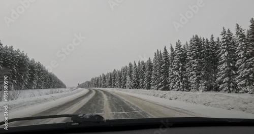 Smooth Vehicle POV Driving along Snowy Winter Highway through Dense Spruce Forest on Overcast Day with Natural Parallax effect for Transportation Logistics and Safe Winter Driving Campaign Scene