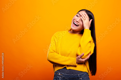 Cuadro en lienzo Asian woman smiles and playfully hides her face, expressing a shy yet happy demeanor, standing against isolated background