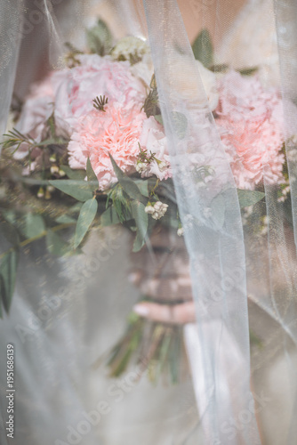 Wedding bouquet under the bride veil. The bride is holding a bouquet