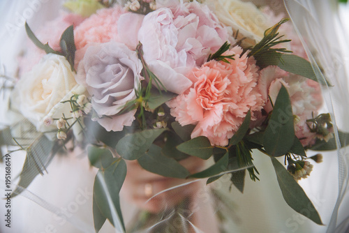 Wedding bouquet under the bride veil. The bride is holding a bouquet