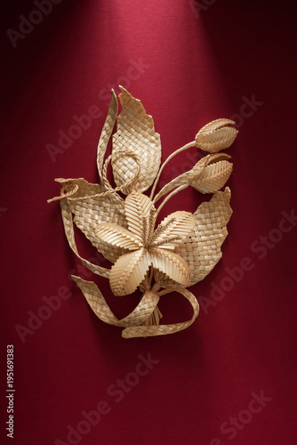 Decoration of straw on a red background. Branch with flowers. Boutonniere made out of straw. Brooch. Straw weaving.