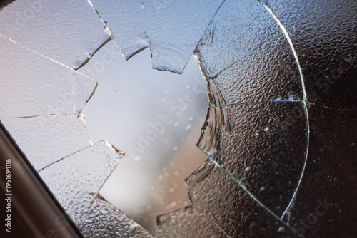 Φωτογραφία smashed window with shattered glass fragments and cracked surface, showing damag
