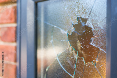 smashed window with shattered glass fragments and cracked surface, showing damage from impact or vandalism on a building exterior