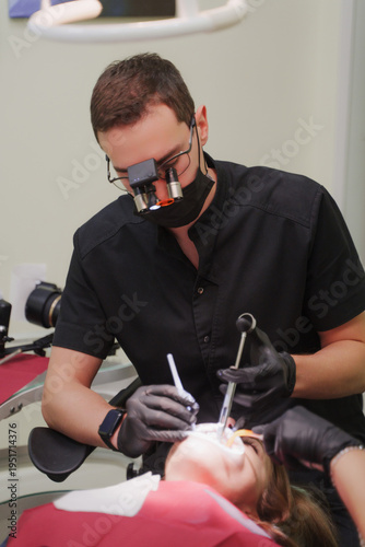The dentist administers anesthesia to the patient. Dental treatment in a private medical clinic. The patient is injected with the drug from a syringe into the gum. Vertical photo.