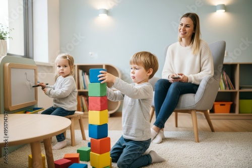 Bright clean children's play area indoor, boy building block tower at low table, sister drawing on magnetic board, mother nearby on phone. AI generative
